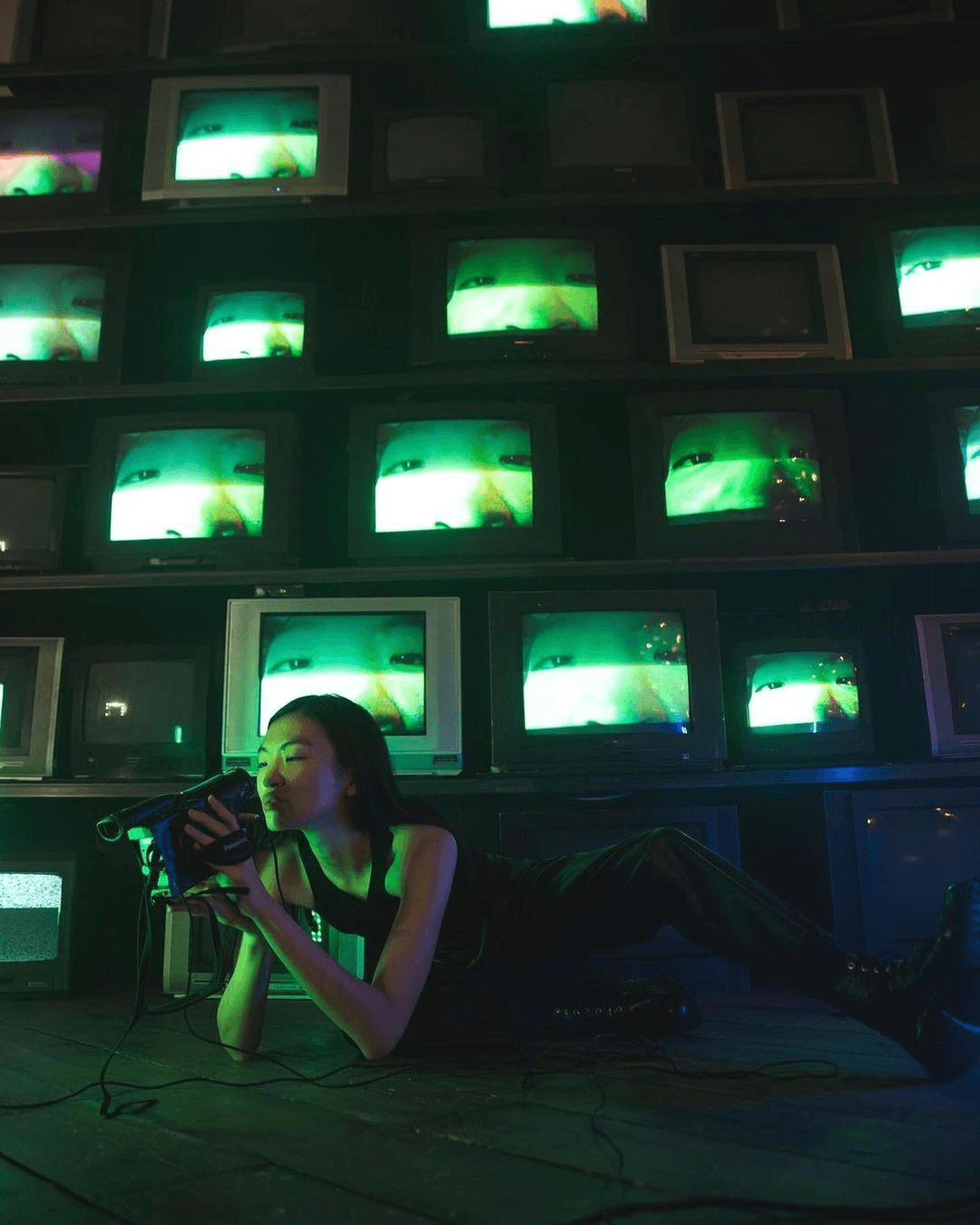Person lying down in from of a wall of CRT screens